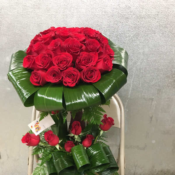 Large bouquet of red roses with glossy green leaf wrapping