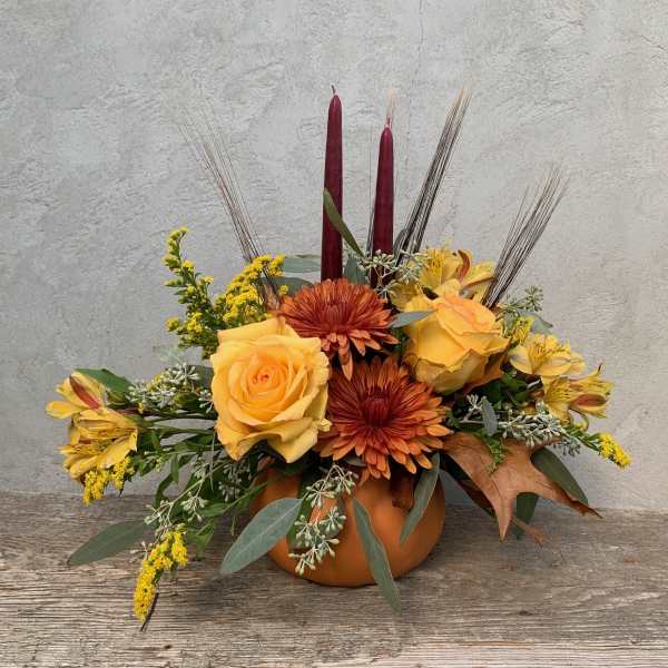 Autumn floral arrangement in a pumpkin vase with yellow roses and orange mums