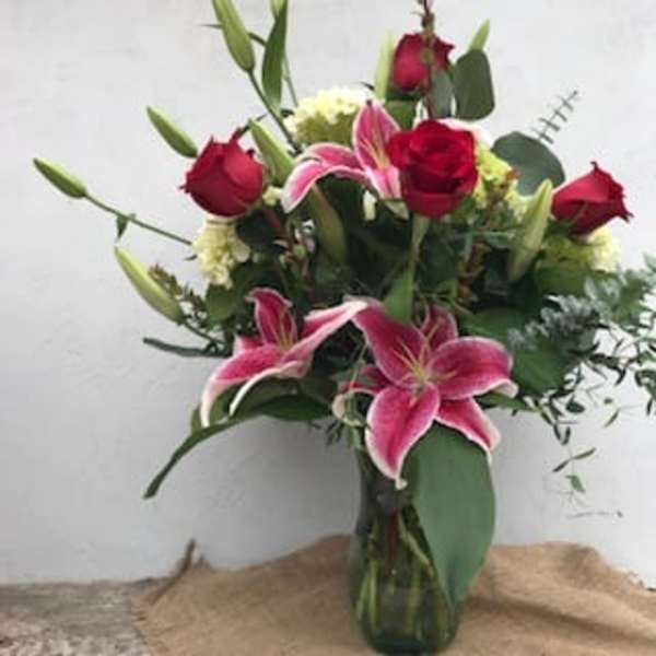 Bouquet of pink lilies and red roses in a glass vase