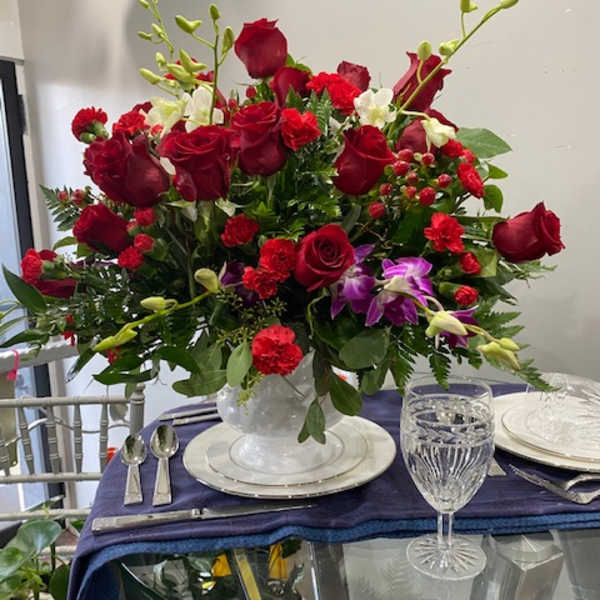 Red rose centerpiece in a clear glass vase on a set table