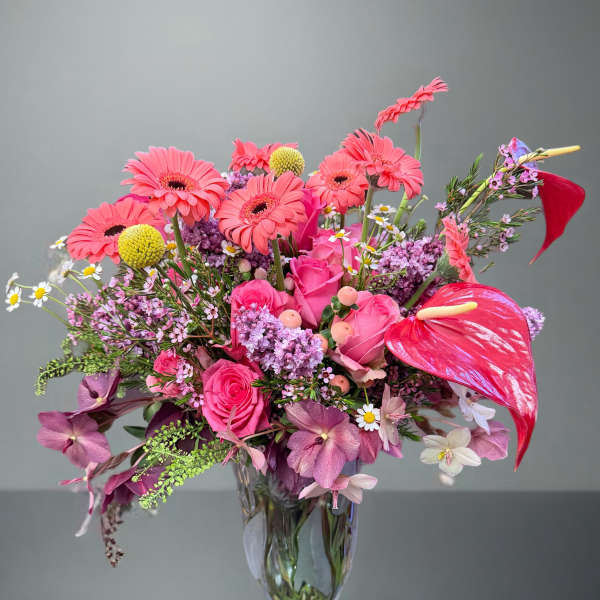 Pink mixed bouquet in a clear glass vase with gerbera daisies and roses