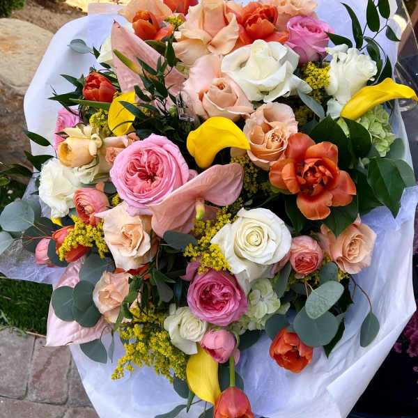 Mixed bouquet of roses, tulips, calla lilies, and anthurium in white wrap