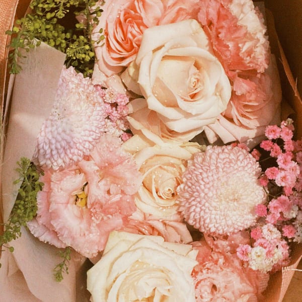 Bouquet of blush and cream roses with pink blooms in paper wrap