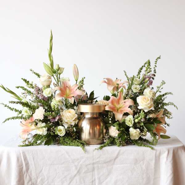Floral centerpiece with lilies and roses around a gold urn