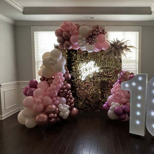 Pink and white balloon arch with a lit "16" sign and gold backdrop