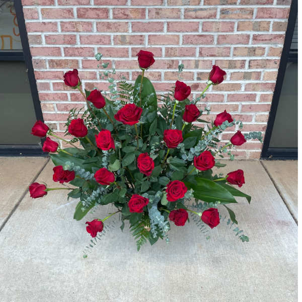 Arrangement of red roses with greenery on the ground