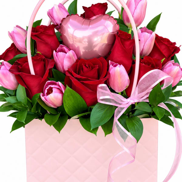 Pink tulips and red roses arranged in a pink gift box with a heart balloon