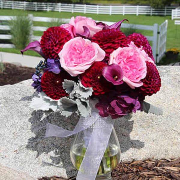 Pink and burgundy bouquet in a glass vase with a ribbon