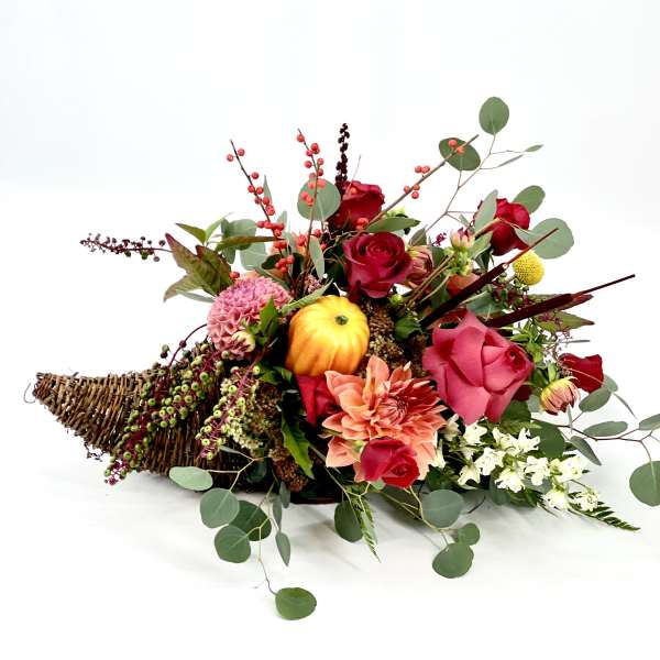 Low floral arrangement with red and pink blooms in a wicker basket