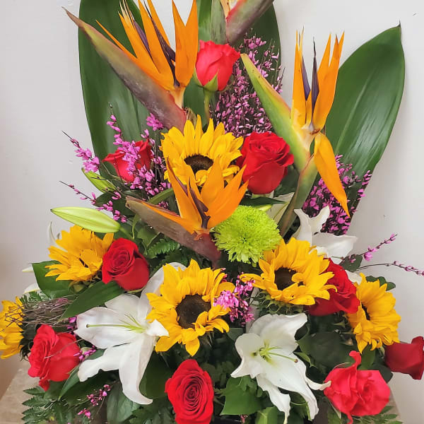 Tropical arrangement with red roses, sunflowers, and white lilies