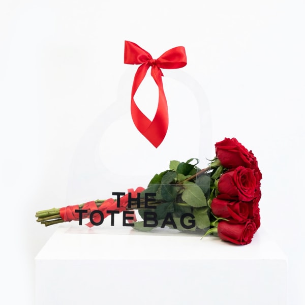 Bouquet of red roses in a clear tote bag with a red ribbon