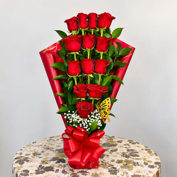 Bouquet of red roses wrapped in red paper with a bow