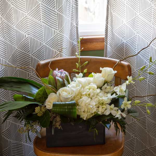 White floral arrangement in a dark rectangular container with long branches