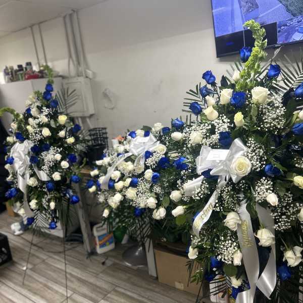 Tall standing floral sprays with blue and white roses and white ribbons