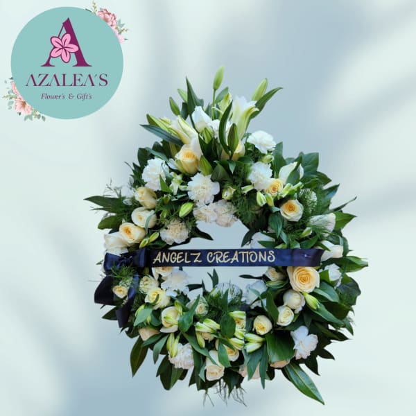 White and cream floral wreath with lilies, roses, and carnations