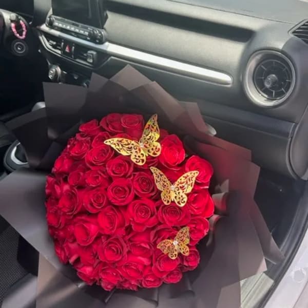 Bouquet of red roses wrapped in black paper with butterfly decorations