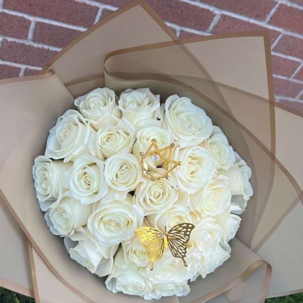Bouquet of white roses wrapped in tan paper with gold butterfly accents