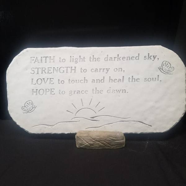 Engraved stone plaque with a hopeful quote on a small stand