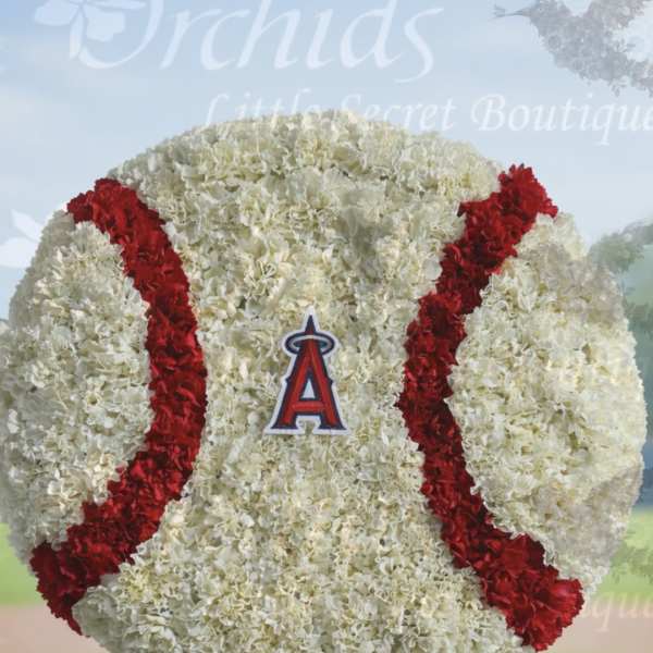 Large round white and red floral arrangement shaped like a baseball on a wooden stand
