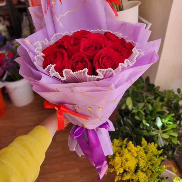 Bouquet of red roses wrapped in lavender paper with red ribbons
