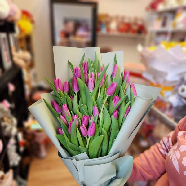 Bouquet of pink tulips wrapped in pale paper with a ribbon