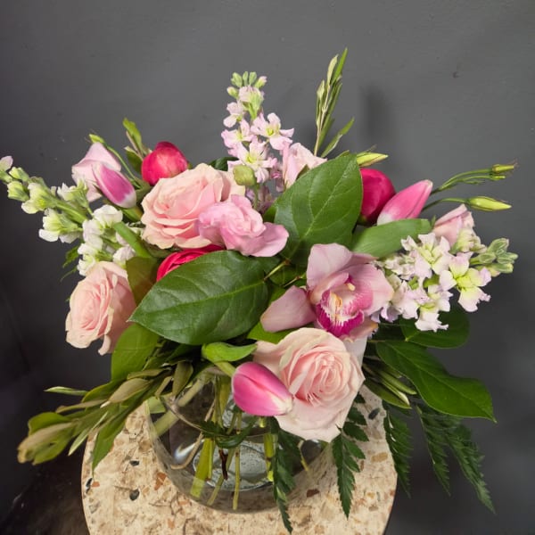 Pink roses and orchids arranged in a clear glass vase