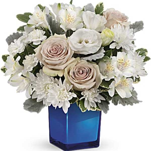 White and blush flowers arranged in a blue glass vase