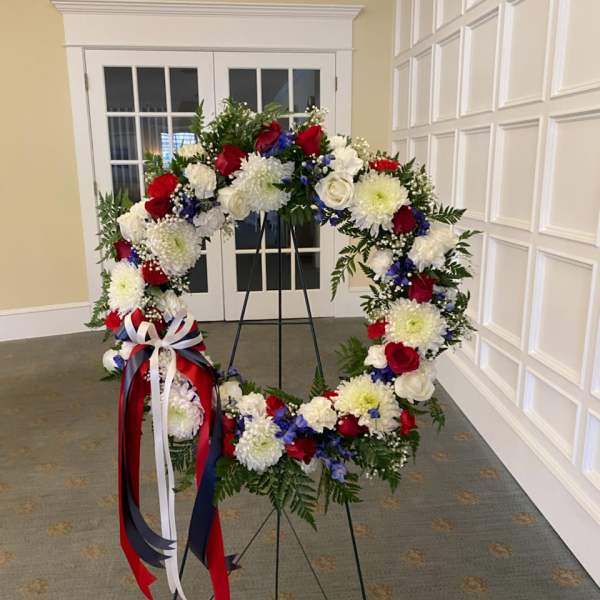 Large floral wreath on a stand with red, white, and blue flowers