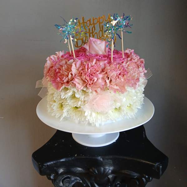 Pink and white flower cake with a Happy Birthday topper