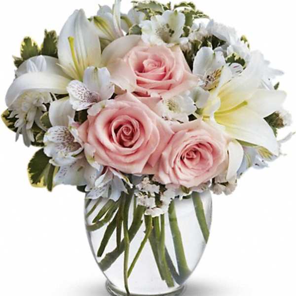 Pink roses and white lilies arranged in a clear glass vase