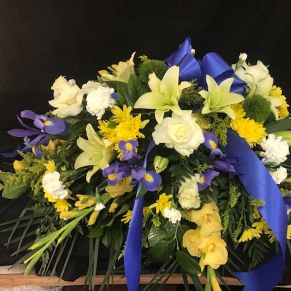 Large floral spray with white, yellow, and purple flowers and blue ribbon