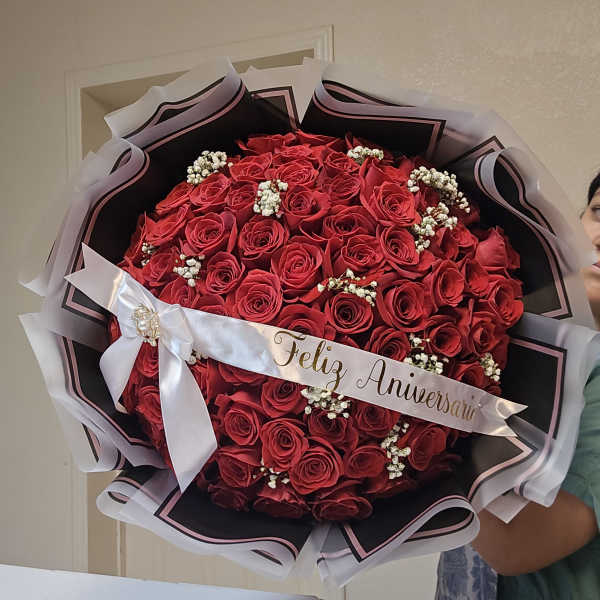 Large bouquet of red roses with a white anniversary ribbon