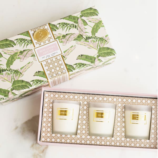 Three scented candles in a pink gift box with tropical-patterned packaging.