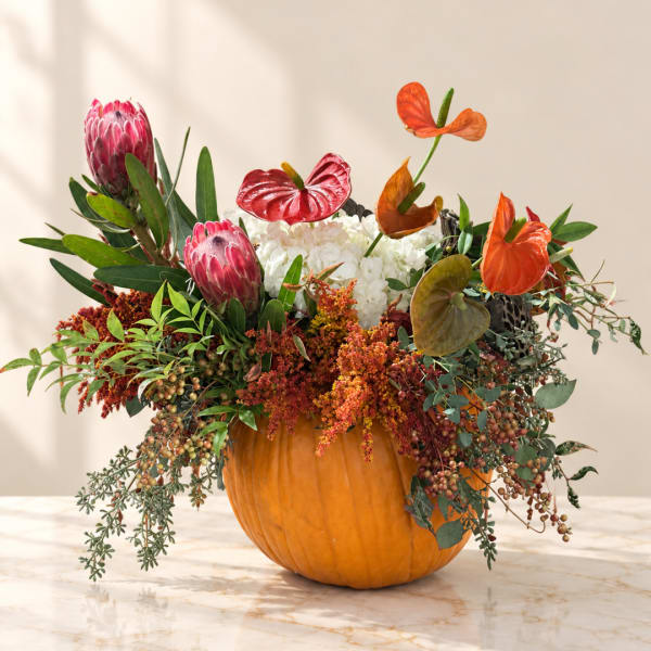 Floral arrangement in a pumpkin with pink and orange blooms