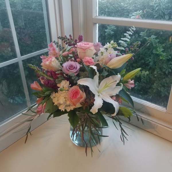 Mixed bouquet of pink and white flowers in a clear glass vase