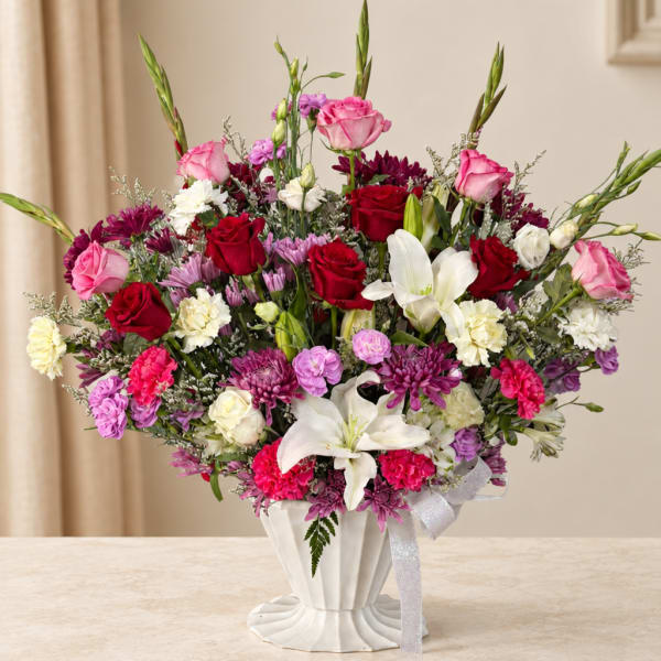 Large mixed bouquet of roses, lilies, and chrysanthemums in a white vase