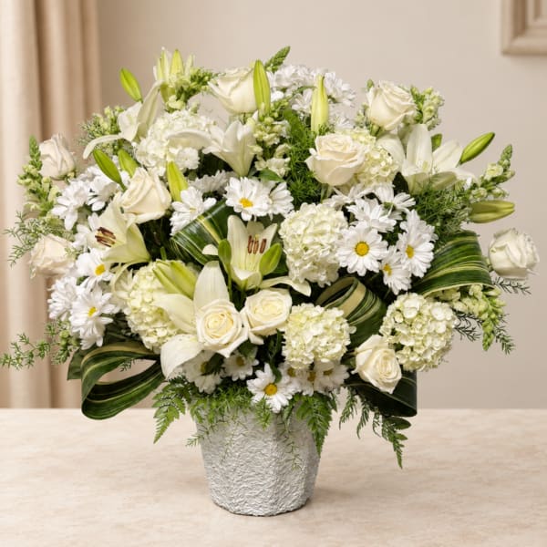 White roses, lilies, and daisies arranged in a textured vase