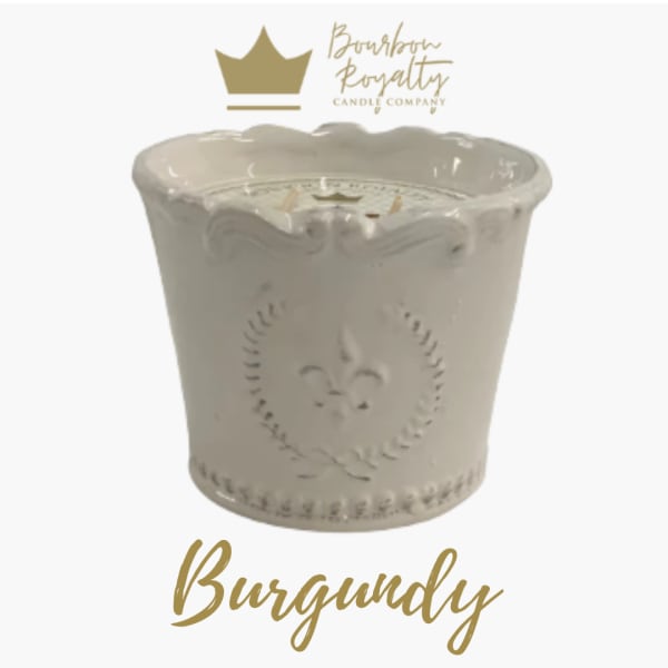 White decorative candle in a ceramic container with gold branding