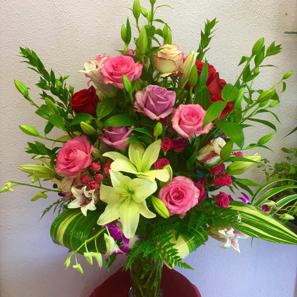 Mixed bouquet of pink and red roses with lilies in a glass vase