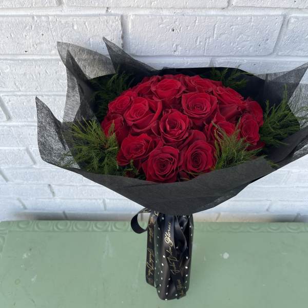 Bouquet of red roses wrapped in black paper with a ribbon