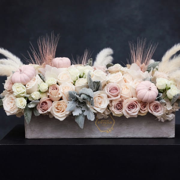 Pastel roses arranged in a rectangular box with small decorative pumpkins