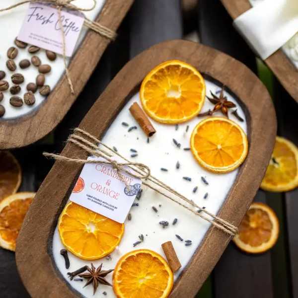 Candle in a wooden tray with dried orange slices and spices