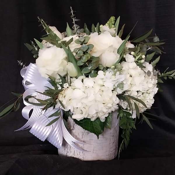 White floral arrangement in a birch-style container with a ribbon bow