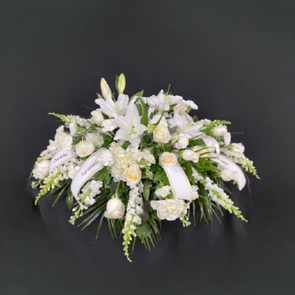 White floral spray with lilies and roses on a dark background