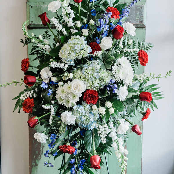 Large standing floral spray with red, white, and blue flowers on an easel.
