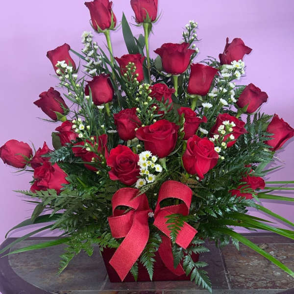 Red roses arranged in a red box with a ribbon bow