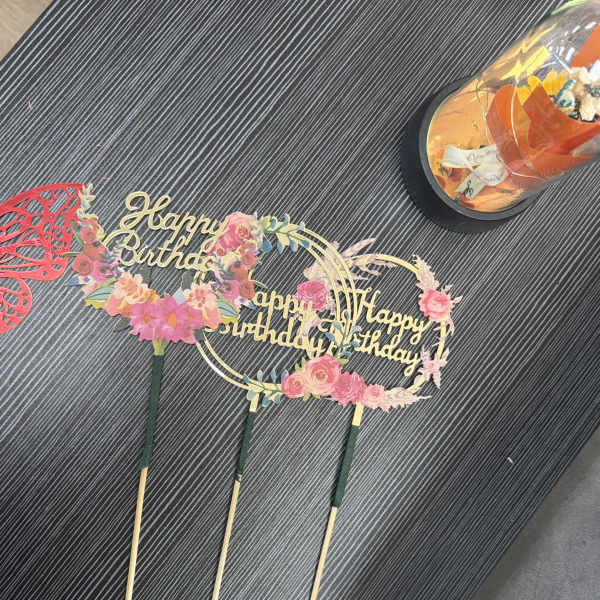 Birthday cake toppers with floral decorations and gold lettering