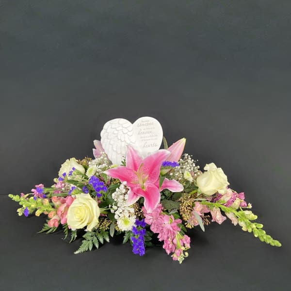 Sympathy floral arrangement with pink lilies and cream roses around a heart memorial plaque