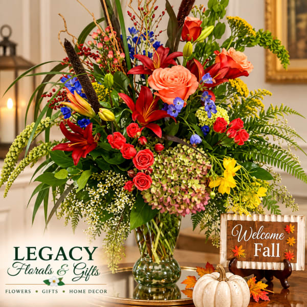 Colorful mixed bouquet in a glass vase with a fall welcome sign and pumpkin decor