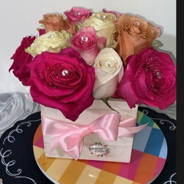 Pink and cream roses arranged in a box with a pink ribbon